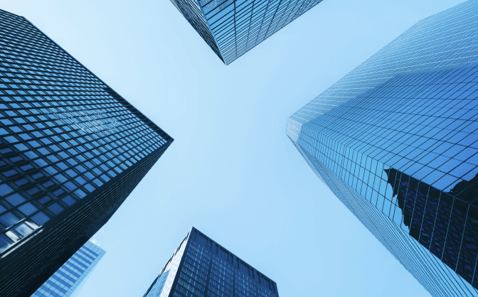 Fotografía en plano contrapicado de un grupo de 4 edificios azules de instituciones financieras y servicios.