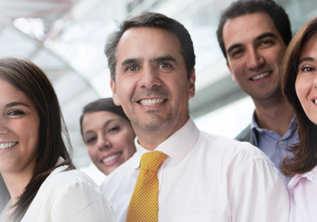 Foto de un hombre adulto sonriendo, acompañando de un grupo de personas del equipo de banca inversion bancolombia.